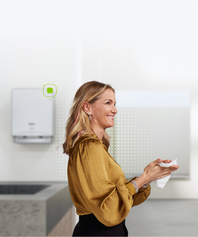 Woman in restroom drying her hands with paper towel in a smart restroom.